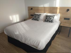 a large white bed with two pillows on it at Hotel Entrerailes in Casalarreina