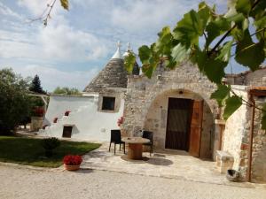 eine Außenansicht eines Gebäudes mit einer Tür und einem Tisch in der Unterkunft Trulli La collinetta in Martina Franca