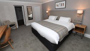 a hotel room with a large bed and a desk at Green Lodge, Wirral by Marston's Inns in Hoylake