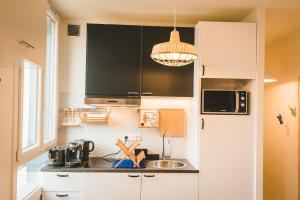 una cocina con armarios blancos y fregadero en My Cosy Home Paris Villejuif, en Villejuif