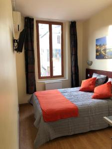 sypialnia z łóżkiem z czerwonymi poduszkami i oknem w obiekcie Hotel Victory w Marsylii