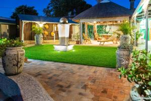 a patio with a lawn and a fountain in a yard at De Helling Self Catering in Brackenfell