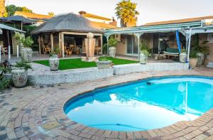 a swimming pool in a backyard with a gazebo at De Helling Self Catering in Brackenfell
