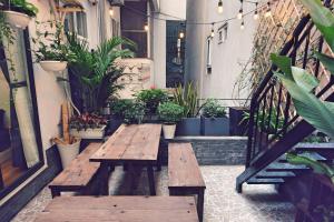 an outdoor patio with wooden benches and potted plants at The Gallery House in Hanoi