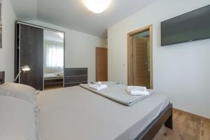 a white bedroom with a bed and a large mirror at Villa Nespola Penthouse in Cavtat