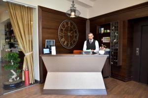 a man sitting at a bar in a hotel room at Hotel Capitolina City Chic in Cluj-Napoca