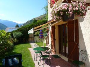 a patio with chairs and a table and flowers at PLEIN SOLEIL appartement avec GARAGE pour SKI TROIS VALLEES et CURE THERMALE in Brides-les-Bains +5 photos