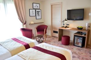 a hotel room with two beds and a television at Hotel Capitolina City Chic in Cluj-Napoca