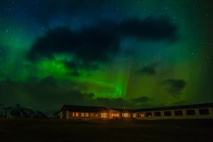an aurora over a house with a building in the foreground at Hotel Langaholt in Langaholt