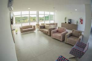 uma sala de espera com sofás, cadeiras e janelas em HOTEL HPR em Vitorino