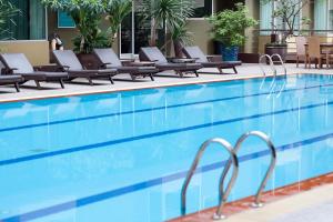a swimming pool with lounge chairs next to a hotel at Dynasty Grande Hotel in Bangkok