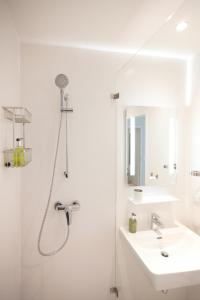 een witte badkamer met een douche en een wastafel bij URBANAUTS FLATS Cubierta in Linz