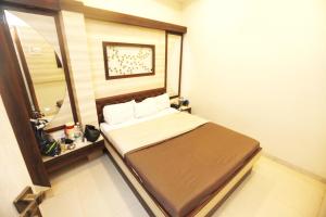 a small bedroom with a bed and a mirror at Hotel Al Moazin in Mumbai