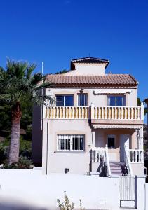 ビジャマルティンにあるFabulous detached large villa 5 bedrooms 3 bathrooms backing onto Villamartin Golf Courseのヤシの木が目の前に広がる白い家