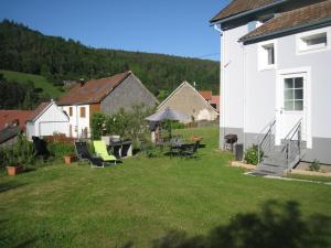 a yard with chairs and a table with an umbrella at Gite en pleine verdure au coeur du village in Lapoutroie