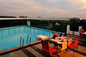 a table and chairs next to a swimming pool at Copper Folia in Kozhikode
