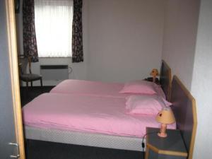 Schlafzimmer mit einem Bett mit rosa Bettwäsche und einem Fenster in der Unterkunft Hotel Saint-Hubert in Malmedy