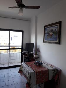 ein Wohnzimmer mit einem Tisch und einem Deckenventilator in der Unterkunft Apartamento inteiro in Praia Grande