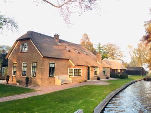 een groot bakstenen huis naast een rivier bij Gieters Mooist in Giethoorn