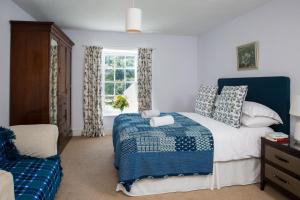 a bedroom with a blue and white bed and a window at The Old House, Llwyn Madoc in Llanwrtyd Wells