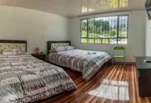 two beds in a room with two windows at Apartamento - ApartaSuite ARGUS in Paipa