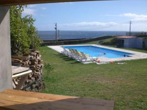 a swimming pool with lounge chairs and the ocean at Azores Residence in Pesqueiro