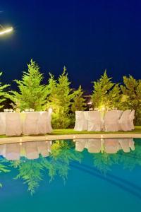 a pool with white chairs and trees at night at Parnis Palace in Athens
