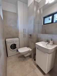 ein Badezimmer mit einem Waschbecken und einer Waschmaschine in der Unterkunft Apartament MALIBU - Aprent in Pobierowo
