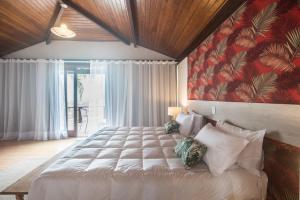 a bedroom with a large bed with a red wall at Ilha Branca Exclusive Hotel in Búzios +86 photos
