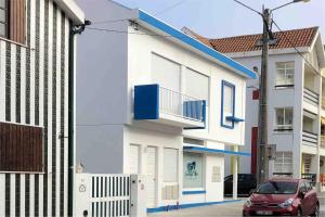 a red car parked in front of a white building at SEA RIA - A casa dos Maria in Costa Nova