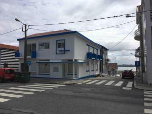 a white building with blue accents on a street at SEA RIA - A casa dos Maria in Costa Nova