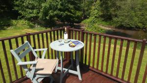 a table and a chair on a deck with a drink at 28 Riverside, Caer Beris Holiday Park in Builth Wells