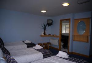 a hotel room with three beds and a television at The Dingle Pub B&B in Dingle