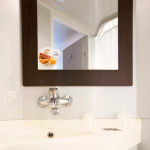 bagno con lavandino e specchio di Premiere Classe Arles a Arles