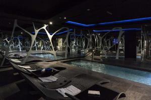 una piscina con sillas en una habitación con luces en A Point Arezzo Park Hotel, en Arezzo