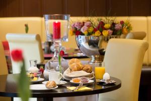 フランクフルト・アム・マインにあるマインガウ ホテルの食べ物と飲み物のテーブルと花のテーブル