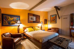 a bedroom with yellow walls and a bed and two chairs at Villa Mogador Piscine et Balnéo in Andernos-les-Bains