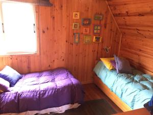 a bedroom with two beds in a log cabin at VISTA MAR casa familiar para 8 personas in Pichilemu +6 photos