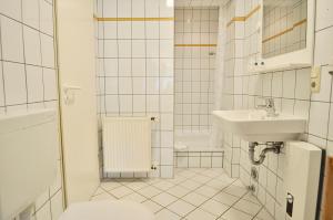 a white tiled bathroom with a sink and a toilet at Gästehaus Schlossgarten in Etelsen +58 photos