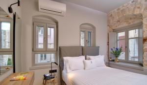 a bedroom with a bed with white sheets and windows at Hotel Boulgari in Ioannina