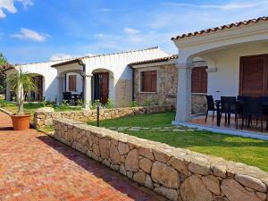 a house with a stone retaining wall and a yard at villette acquamarina Budoni in Budoni