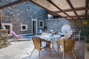 un patio con mesa, sillas y pared de piedra. en Authentic Cretan Stone Windmill, en Sitia