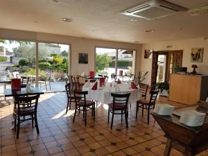 een eetkamer met een witte tafel en stoelen bij Hôtel Restaurant Les Bruyères in Saint-Médard-en-Jalles