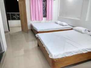 two twin beds in a room with a window at Babusona Homestay in Jaldapara in Mādāri Hāt