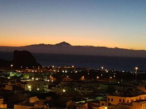 a city at night with a mountain in the background at God´s Finger in Agaete