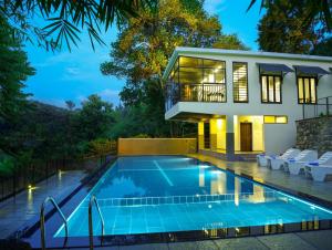 a house with a swimming pool in front of a house at Hotel Treetop in Thekkady