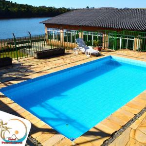 a large blue swimming pool next to a house at Hotel Pousada Icaraí in Poços de Caldas