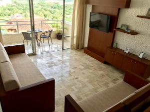 ein Wohnzimmer mit einem TV und einem Balkon in der Unterkunft Hotel Pacifica Departamento 2220 in Ixtapa