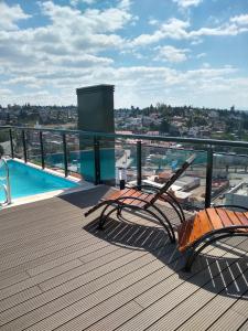 un balcón con 2 sillas y una piscina en Departamento Miralejos 9 en Villa Carlos Paz