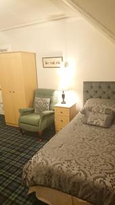 a bedroom with a bed and a chair and a lamp at Crawfords Guest house in Peterhead